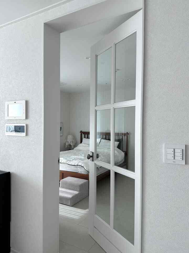 A cozy bedroom with white and brown tones, featuring a wooden bed and a gray pet steps in front