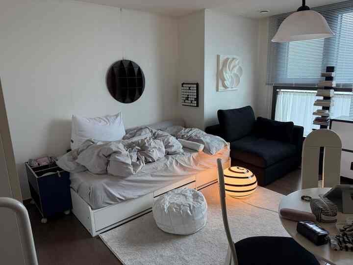 白と黒の色調のワンルーム、シングルベッドと黒いソファが配置されたモダンで落ち着いた雰囲気のあるインテリア