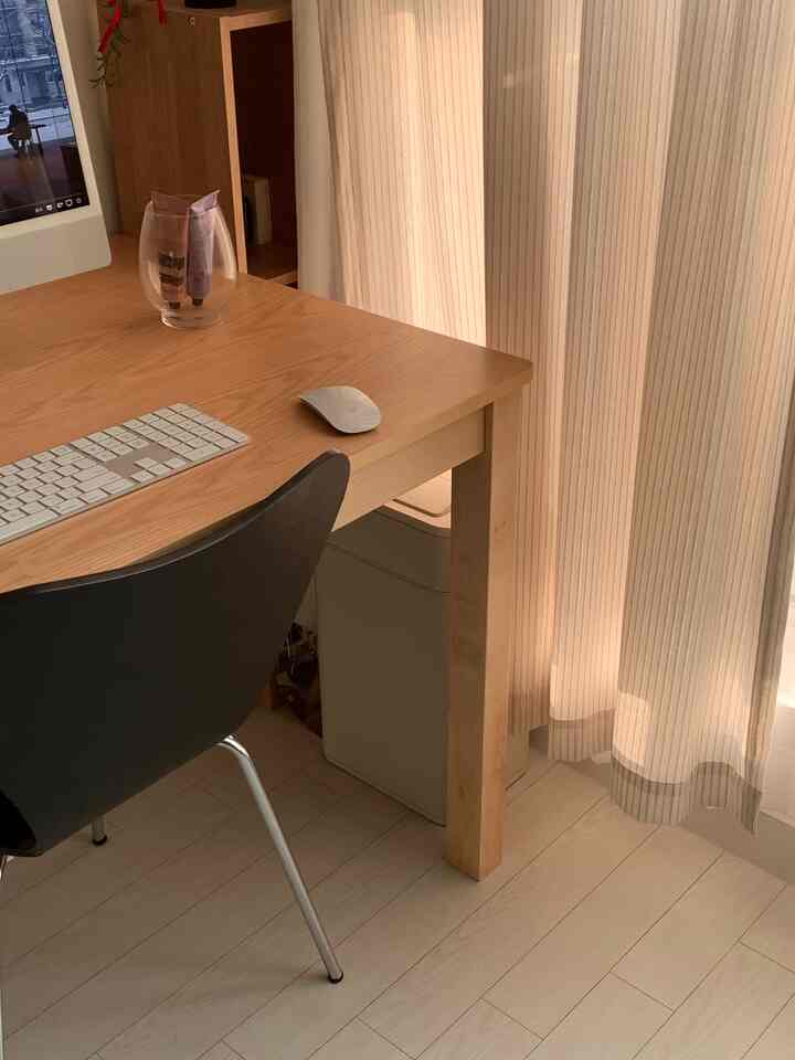 ベージュとナチュラルな色調のワンルーム、デスクとオフィスチェア、自動センサー付きゴミ箱が配置された清潔で快適なホームオフィスのインテリア