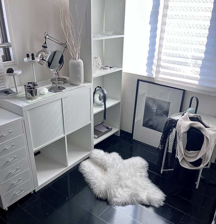 Monotone and silver-toned walk-in closet featuring a vanity, storage units, and simple, clean decor