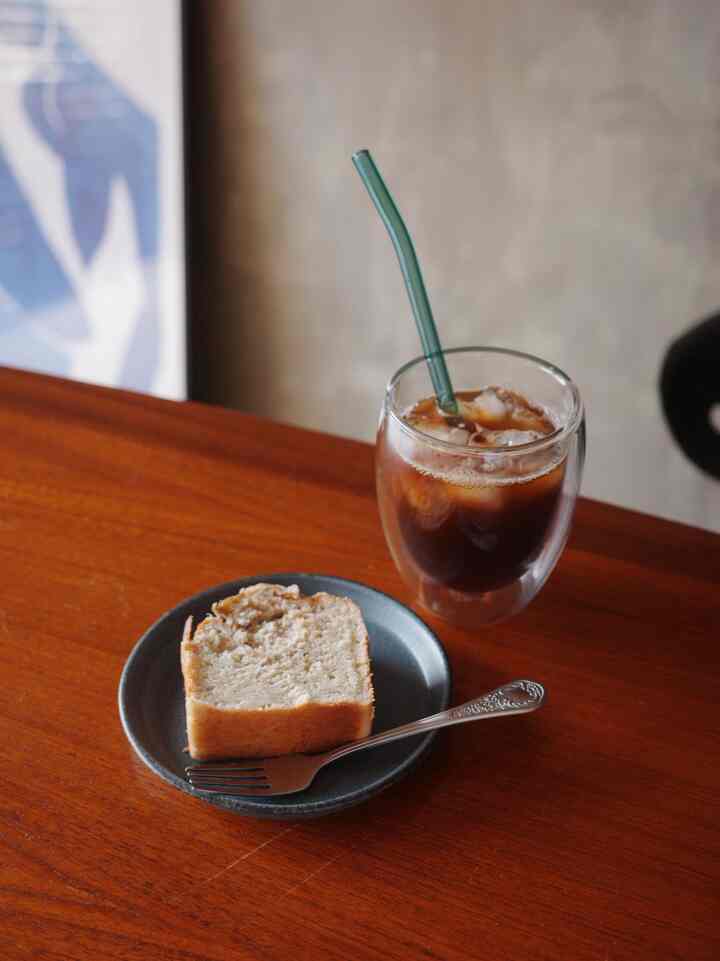 温かみのあるブラウン調のダイニング、テーブルにカトラリーとアイスアメリカーノが置かれた雰囲気のある空間