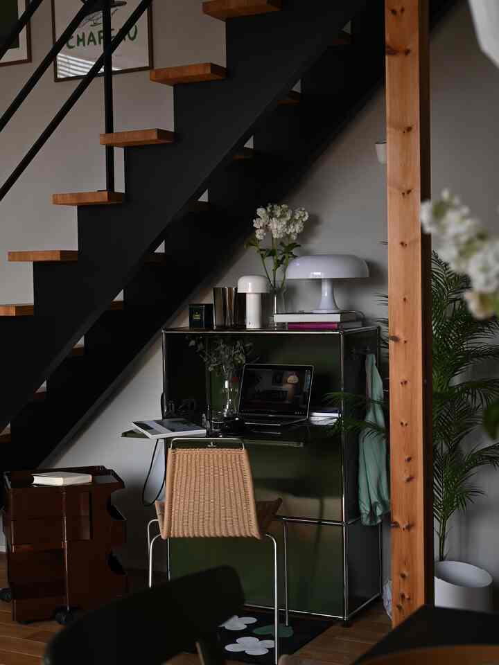木目調と黒を基調としたナチュラルな雰囲気のホームオフィス、緑のUSMキャビネットと木製階段が調和する落ち着いた空間