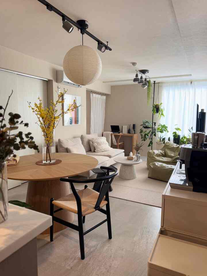 Natural color and light brown toned living and dining room featuring wooden dining table, sofa, and pendant light in cozy remote work space