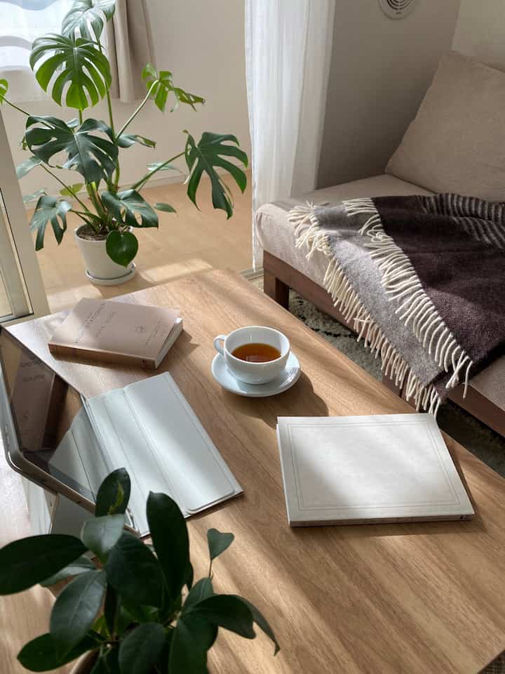 ナチュラルトーンのリビング、ベージュのソファと木製コーヒーテーブル、植物が配置された居心地の良い空間