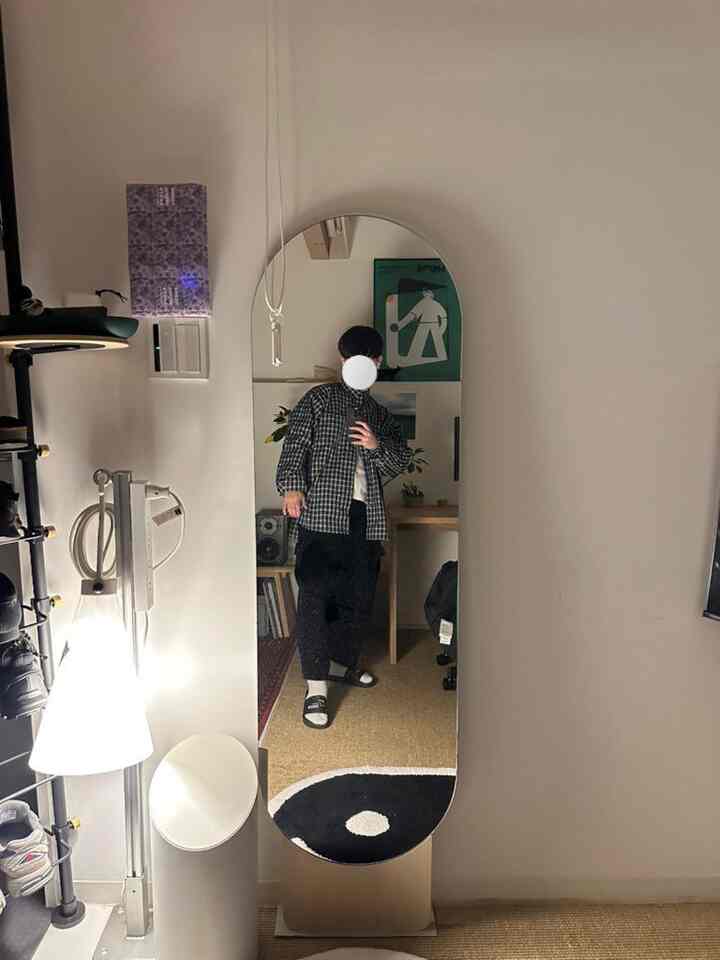 Soft ivory and brown toned single household room featuring a large standing mirror centrally placed with a floor lamp, creating a cozy atmosphere