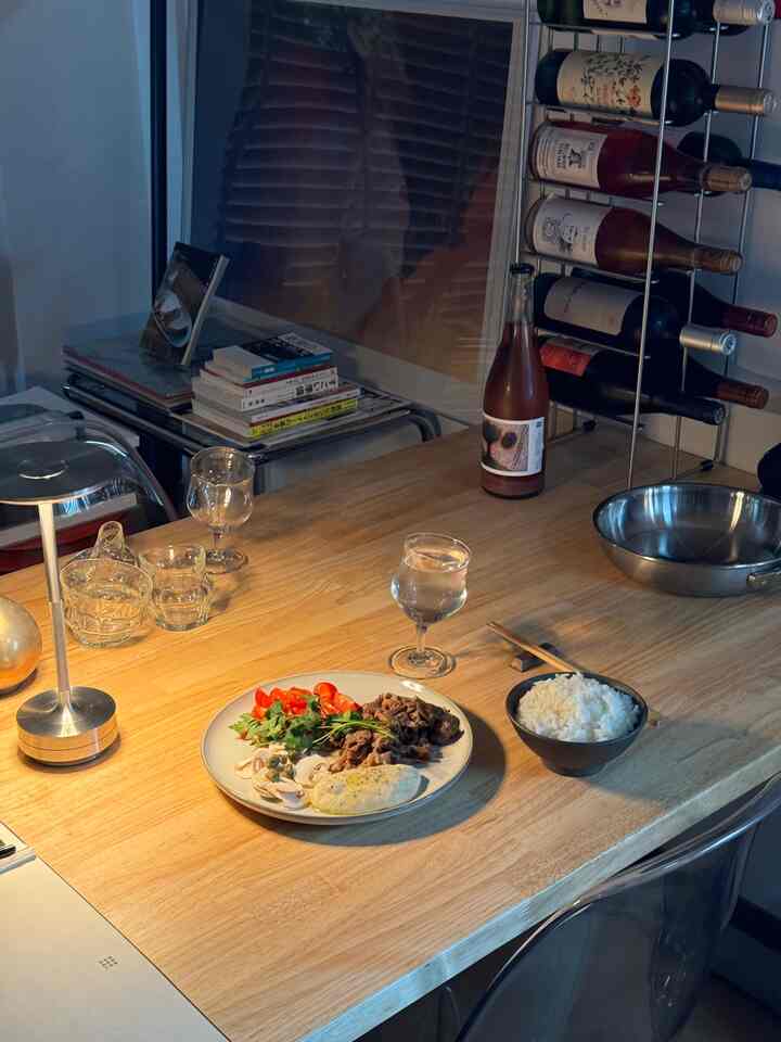 ライトブラウンのダイニングテーブルとワインラックが配置された一人暮らしのキッチンスペース、居心地の良いおうちカフェの雰囲気