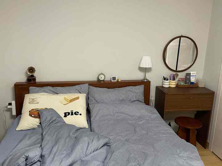 Blue striped bedding with brown wooden furniture in a cozy two-person bedroom space