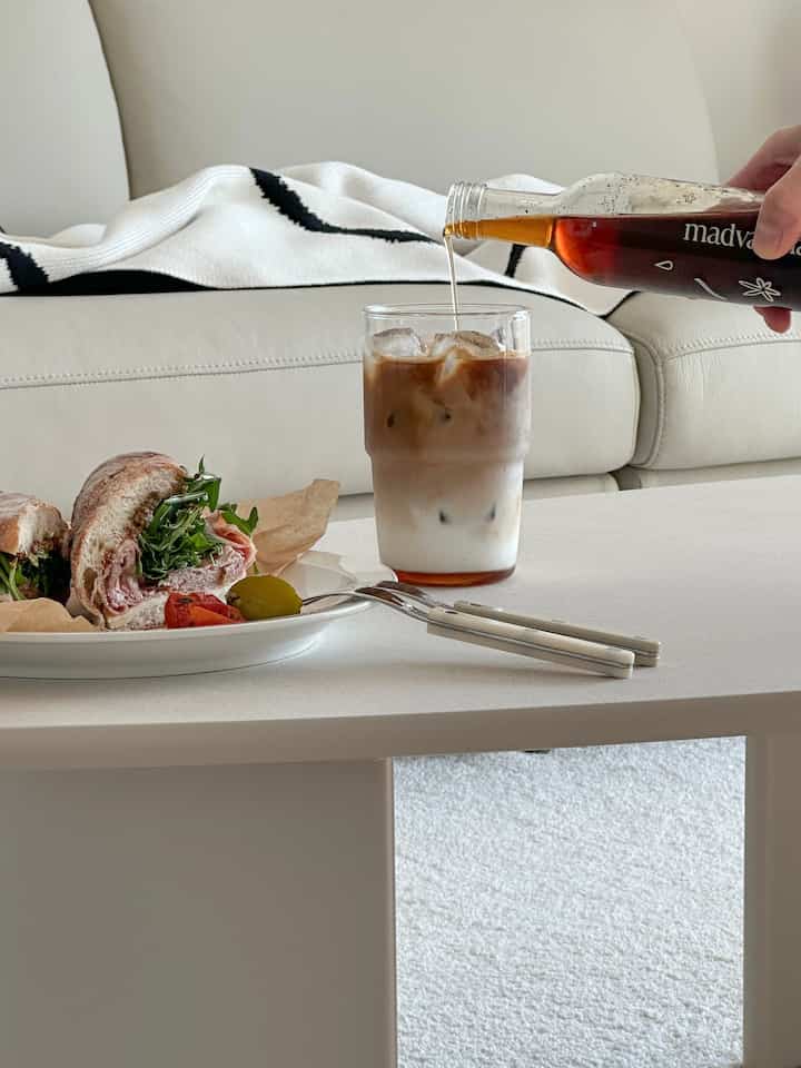 White and black toned living room featuring sofa, coffee table with plate and iced coffee cup in a cozy home cafe setting