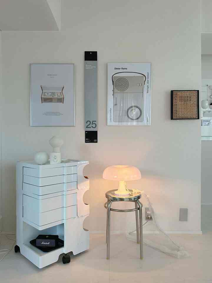 Bright white and silver-toned space with a stainless round stool and kitchen cart, featuring wall decor and a calendar on the wall in a simple interior