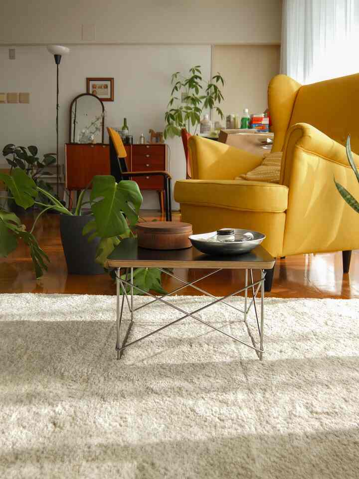 明るい黄色のアームチェアと黒いローテーブルが配置された、自然な色調のリビングスペース