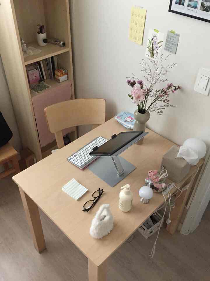 明るい木目調と白い壁の一人暮らしホームオフィス空間、木製の机と椅子に花瓶や小物が配置された雰囲気のあるインテリア