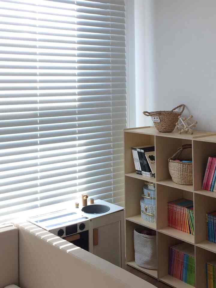 白とベージュのトーンの子供部屋、本棚と子供用キッチン玩具が配置された雰囲気のあるナチュラルな空間