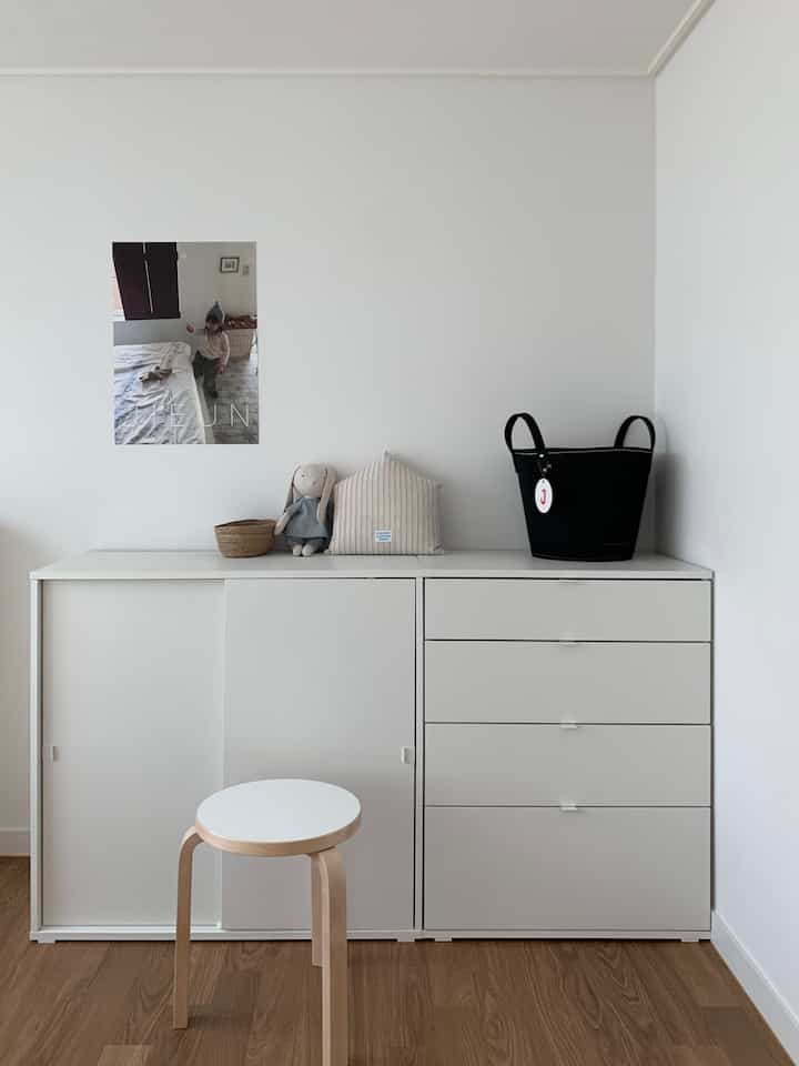 白と木目調の調和が取れた子供部屋、シンプルな収納家具とかわいらしい小物が配置された印象的な空間