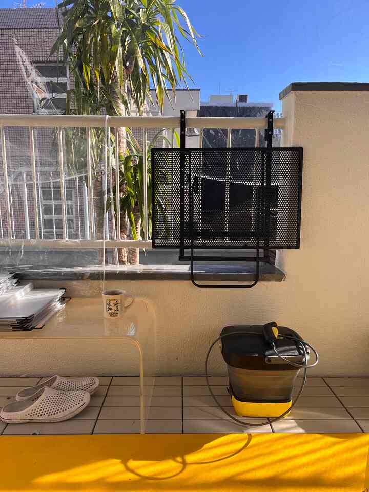 Bright balcony space with yellow accents, white walls and tiled floor, featuring plants and small decorative items