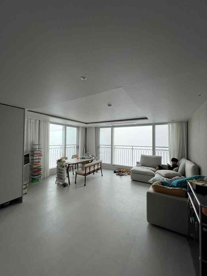 白を基調とした高層アパートのリビング、大きな窓とダイニングテーブル、ソファが配置された雰囲気のある家族空間