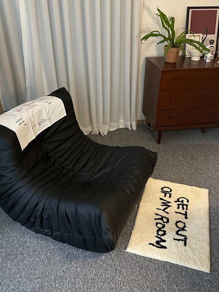 Cozy living room with black sofa, gray rug, and wooden dresser furnishing the space