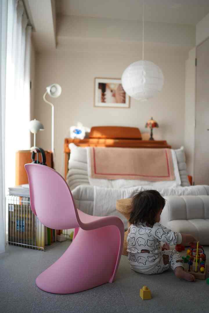 明るいピンクの椅子とおもちゃで遊ぶ赤ちゃんがいる温かみのあるリビング空間