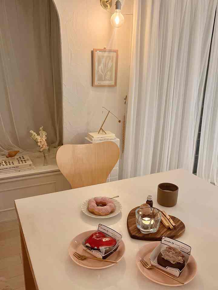 白と木目調のダイニング、テーブルと椅子にデザートとキャンドルが配置された雰囲気のある空間