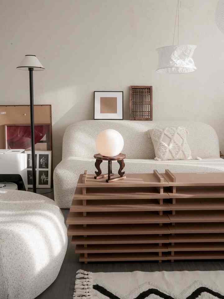 ベージュとウッドトーンのリビング、ブークレ素材のソファと独特な木製コーヒーテーブルが配置された自然でモダンな雰囲気のあるインテリア