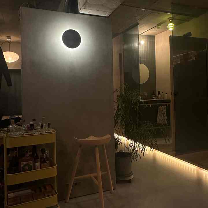 黄色いバーカートと木製スツール、ストリングライトが配置された雰囲気のあるリビング