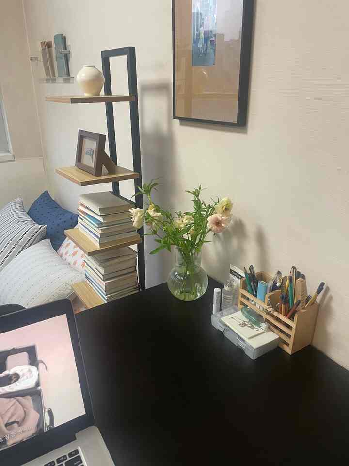 白い壁と黒い机のある一人暮らし用のホームオフィス空間、本棚と花瓶が配置された雰囲気のあるインテリア