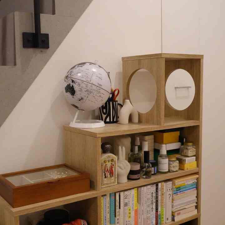 Natural wood-toned storage space with bookshelf placed under stairs, creating a cozy and organized nook