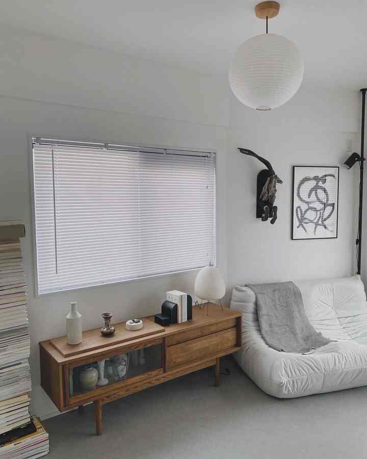 白と茶色の居間、シンプルなソファと木製のサイドボードが配置されたナチュラルで落ち着いたインテリア