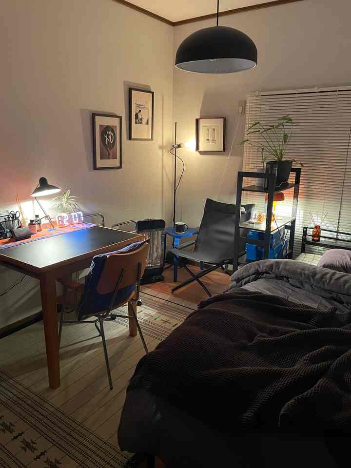 Warm black and natural tone bedroom featuring a desk and camping chair with a cozy atmosphere