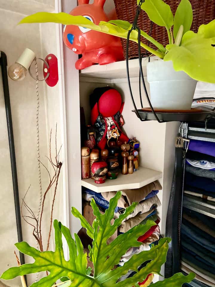 ナチュラルトーンのコーナー収納棚と植物が配置されたヴィンテージ感のあるコンパクトな空間