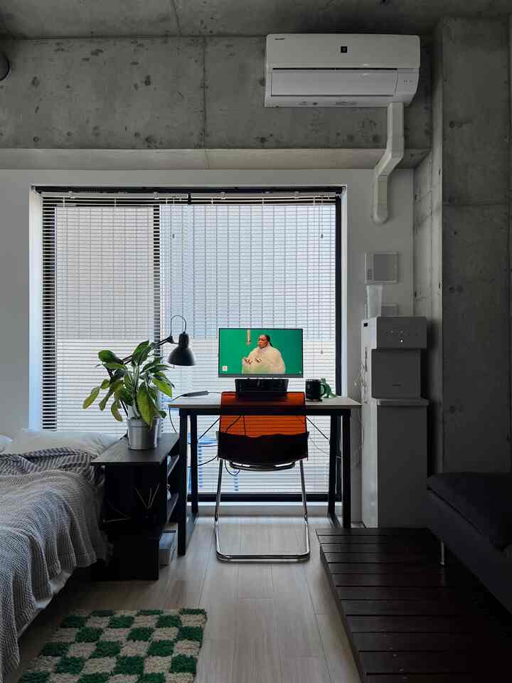 白を基調としたワンルームのワークスペース、木製デスクとオフィスチェアが配置された空間