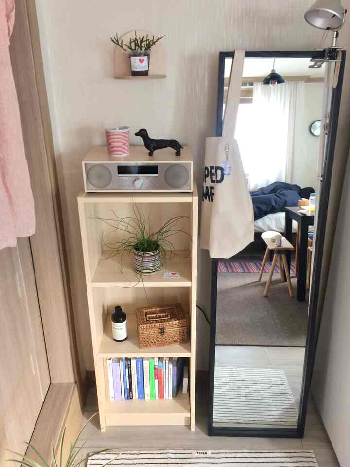 ベージュとホワイトの色調の一人暮らしの空間、書棚と全身鏡が配置された落ち着いたナチュラルスタイルのインテリア