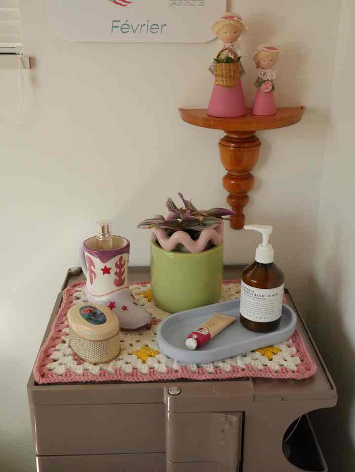 Natural-toned small chest of drawers topped with pink and green plant and charming decorative items in cozy corner