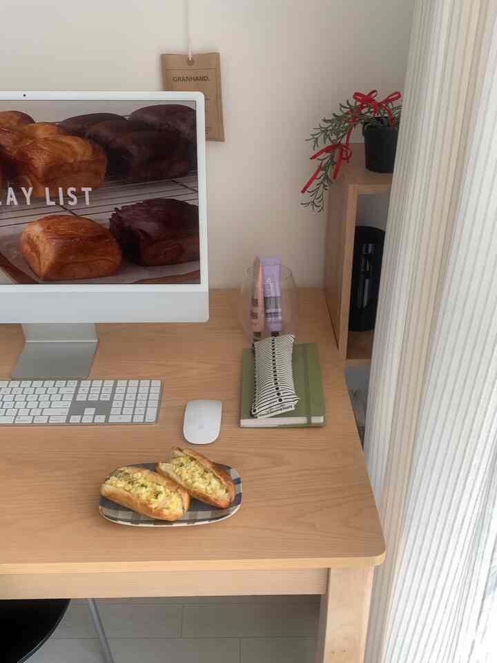 明るいナチュラルカラーのワンルーム、木製テーブルとiMacコンピューターが配置された雰囲気のあるホームオフィス