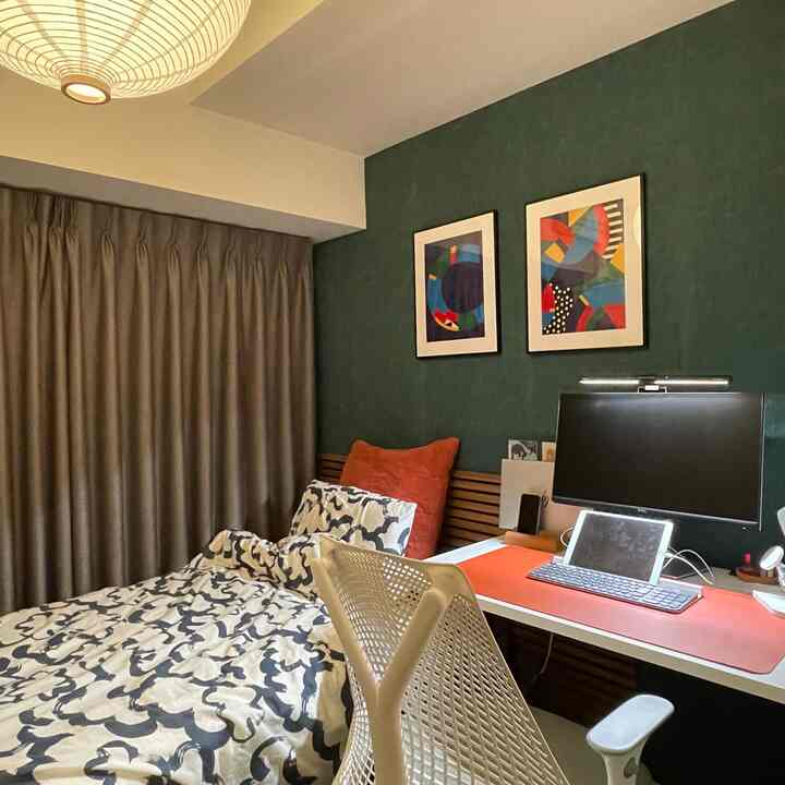 深い緑色のアクセントウォールと木製のヘッドボードを配した、モダンなホームオフィス兼寝室のインテリア