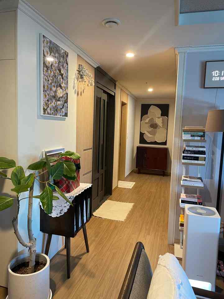 ナチュラルな木目調の細長い玄関ホール、植物とサイドボードが配置された落ち着いた雰囲気の空間