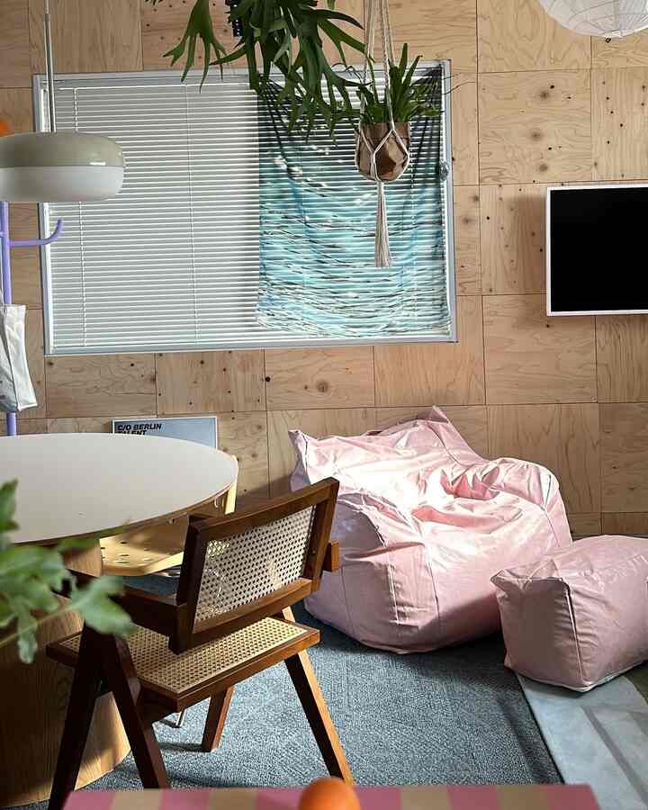 Cozy living room with pink bean bag, rattan chair, and prominent wood tone walls