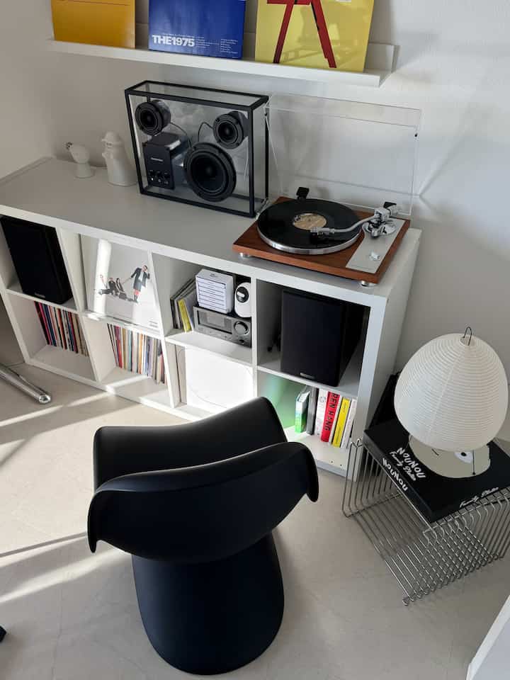 白とモダンな色調のリビング音楽鑑賞空間、アナログターンテーブルと透明スピーカーが配置された印象的なインテリア
