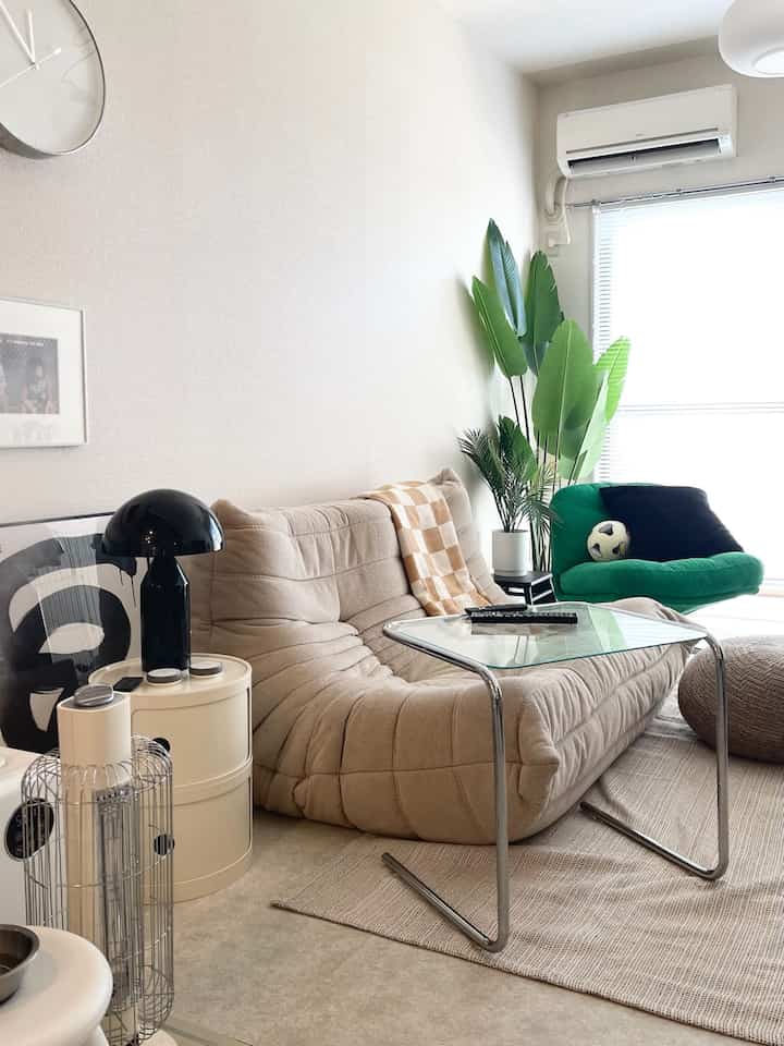 Beige-toned living room featuring sofa, armchair, glass table and green plant in a cozy interior