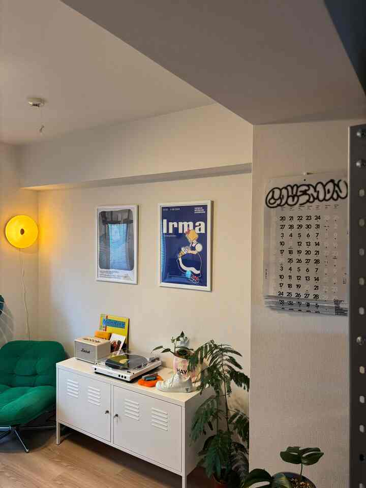 White-walled room featuring a cabinet, green armchair and plants creating a cozy home office atmosphere
