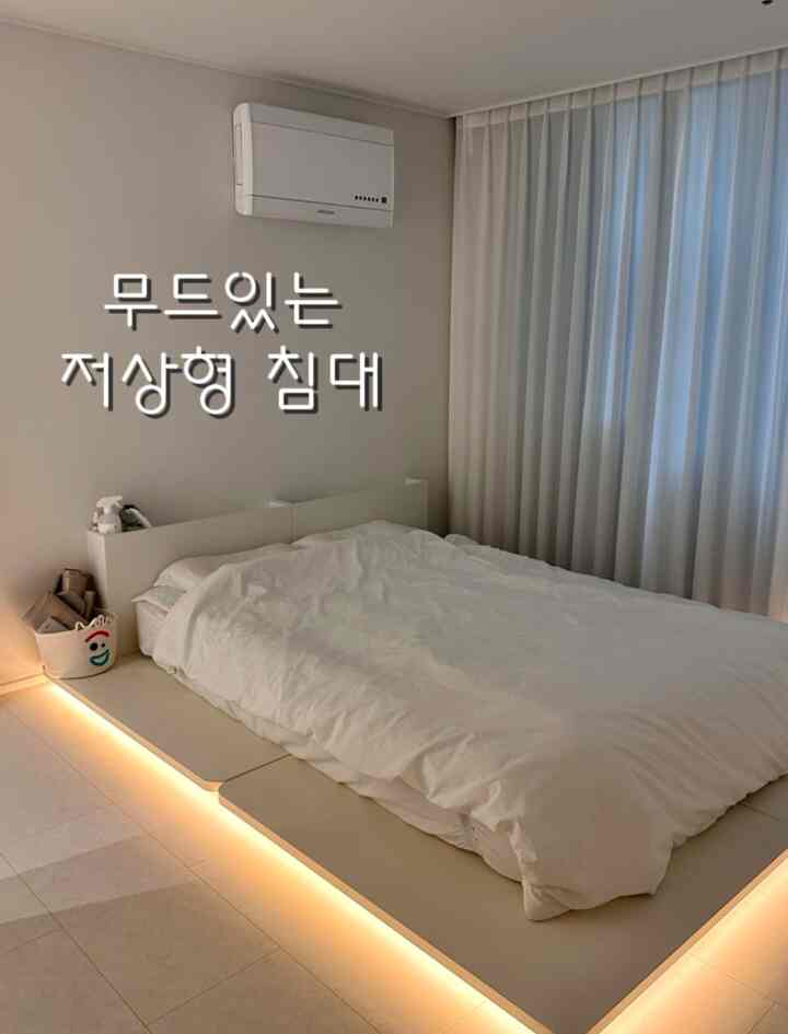 White low-profile bed with soft under-bed mood lighting in a cozy bedroom featuring sheer curtains