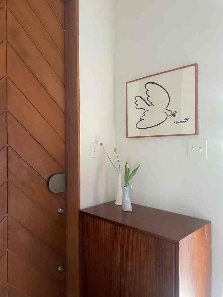 温かみのある木目調の玄関、木製のシューズキャビネットと花瓶が配置されたシンプルな印象の空間