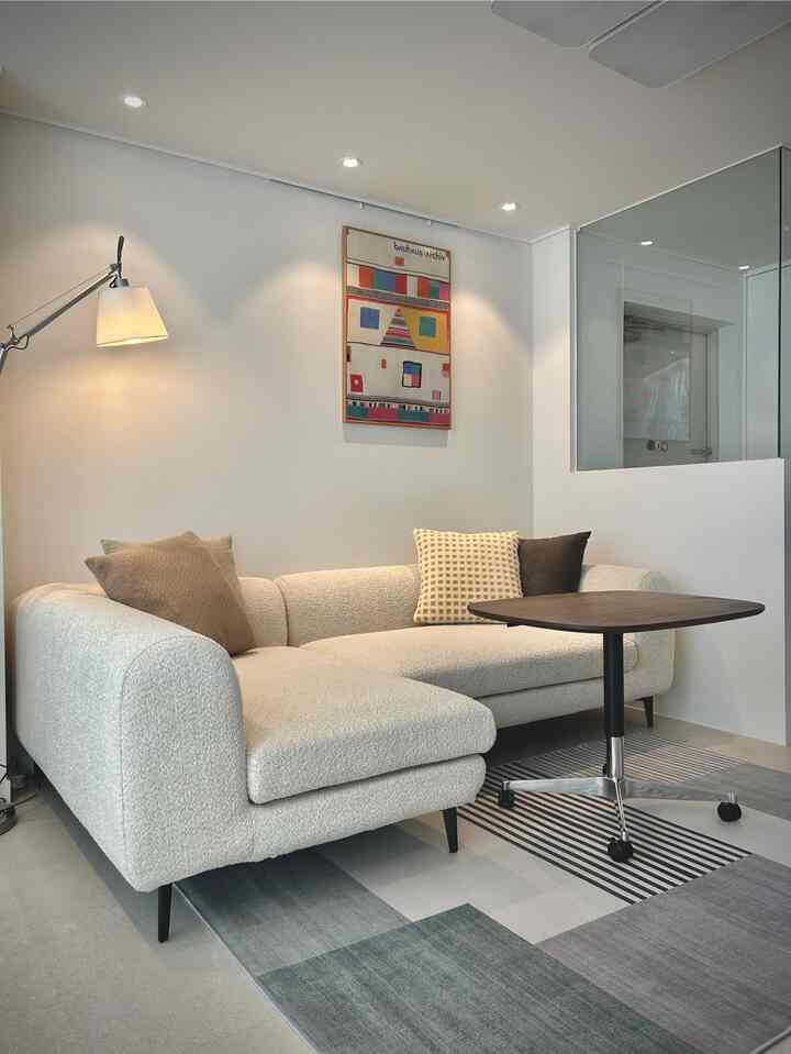 白とグレーのトーンで統一された北欧風リビング、アイボリーのソファとダークウッドのテーブルが配置されたモダンで落ち着いた雰囲気のインテリア