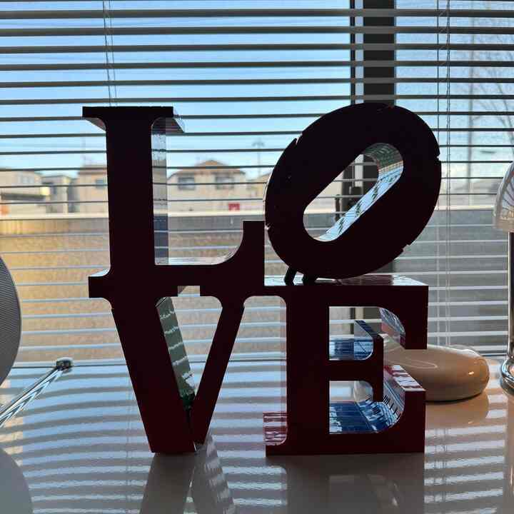 日差しの差し込む窓の前に赤いLOVEオブジェが配置されたインテリアの空間