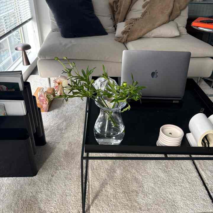 ベージュと黒の色調のリビング、中央にローテーブルと花瓶、ノートパソコンが置かれた自然な雰囲気のインテリア