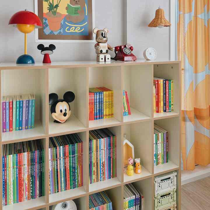 黄色のトーンがある子供部屋、カラフルな本棚とおもちゃが配置されたシンプルで自然な雰囲気のインテリア