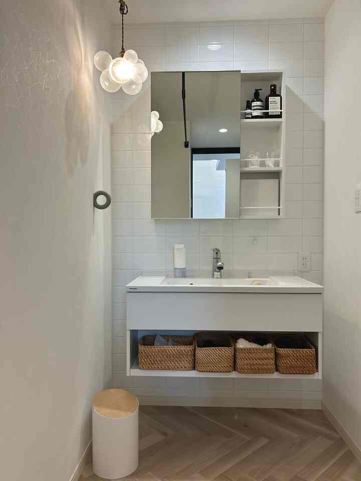 白とナチュラルカラーの浴室、モダンな洗面台とペンダントライトが配置された印象的な空間