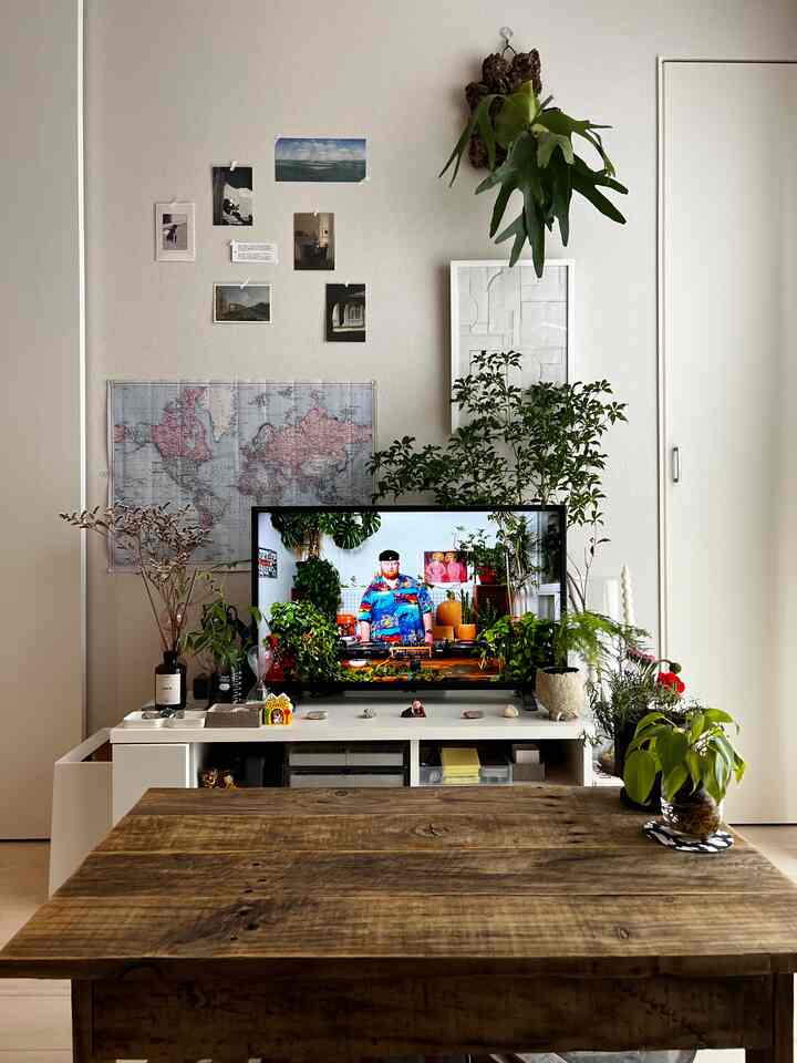 白い壁と木目調テーブル、多様な植物が配置された北欧風のリビングの雰囲気あるインテリア