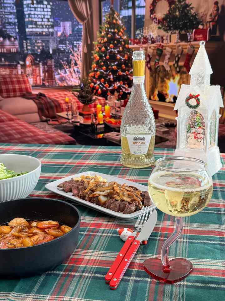 A red and green living room featuring a decorated Christmas tree and a dining table with wine glass and food, evoking a warm home party atmosphere