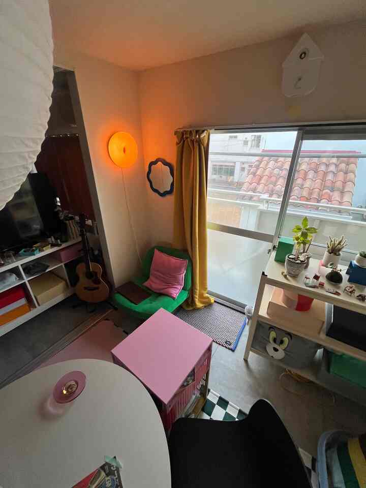 Bright and cozy mid-century modern living space near balcony featuring yellow curtains and green armchair with colorful accents