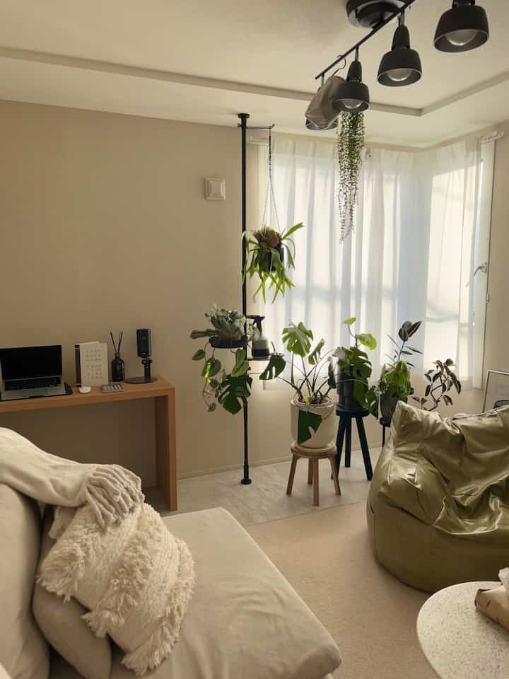 ベージュのナチュラルカラーが特徴のリビング、デスクと多様な植物が配置された落ち着いた和モダンの雰囲気あるインテリア